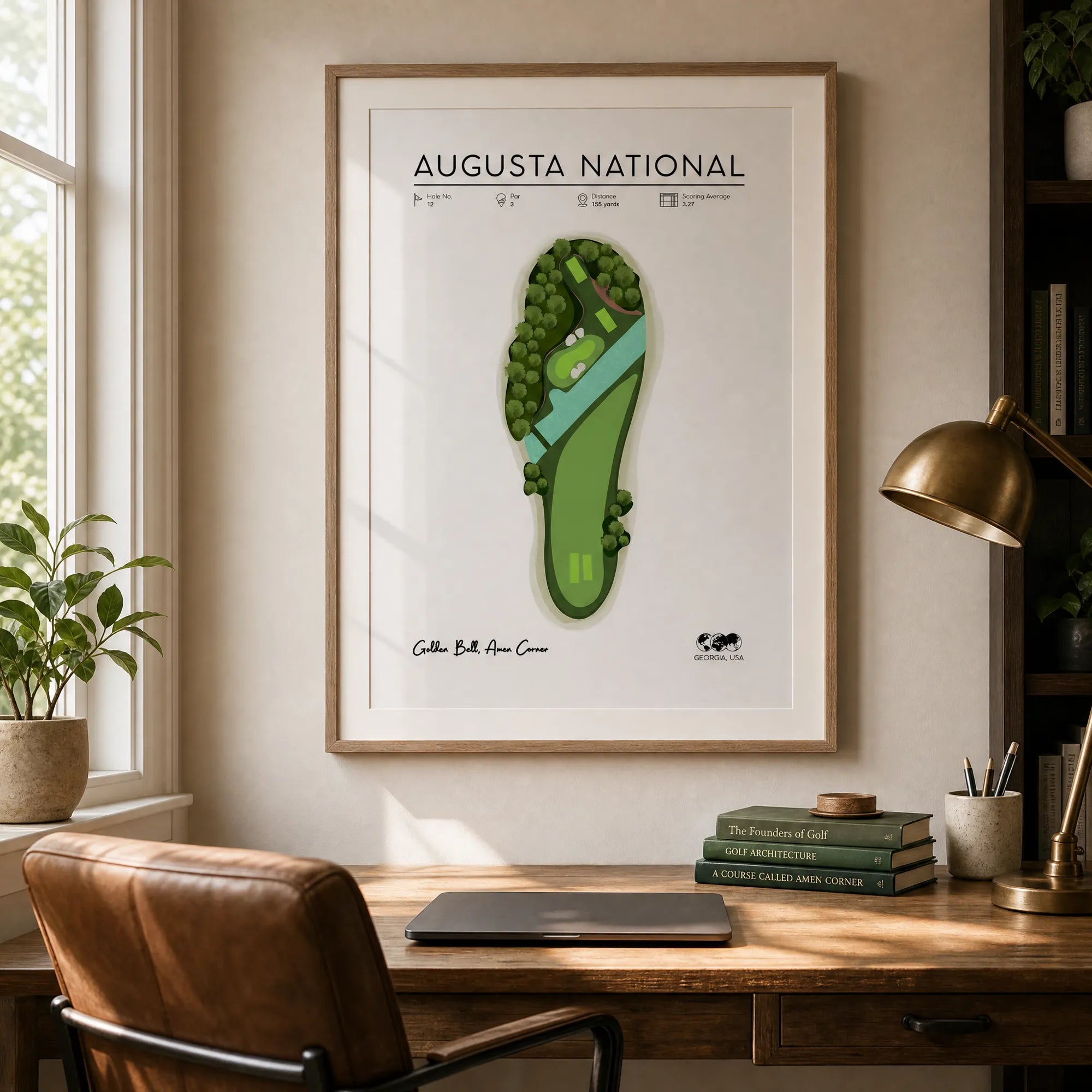 Framed golf artwork print of Hole 12 displayed on a dark wall in a home office, showing the illustrated par-3 course map at full size.