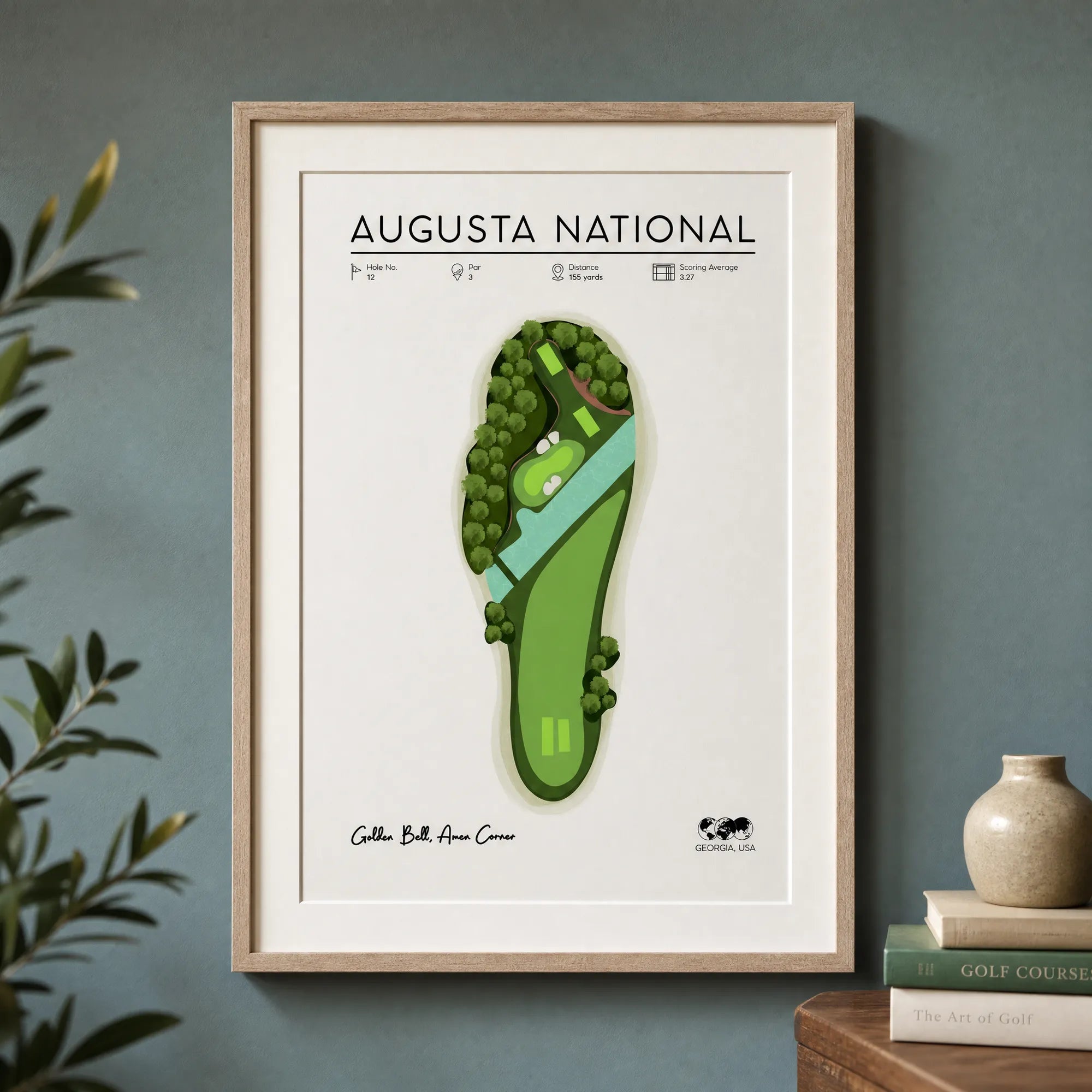Framed golf artwork print of Hole 12 displayed on a dark wall in a home office, showing the illustrated par-3 course map at full size.