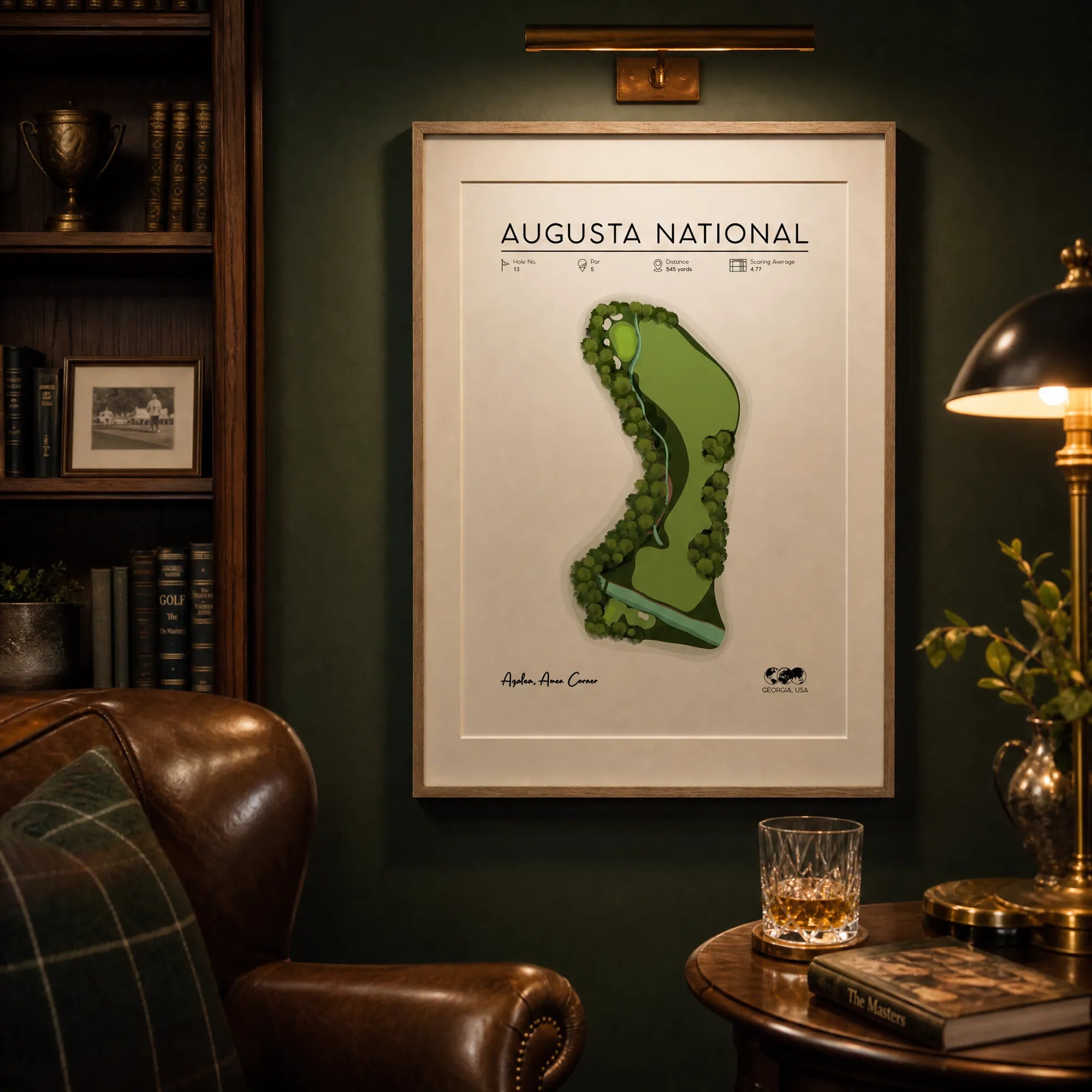 Golf artwork in a book-lined study, framed golf course map print, white wall, leather chair, warm afternoon light