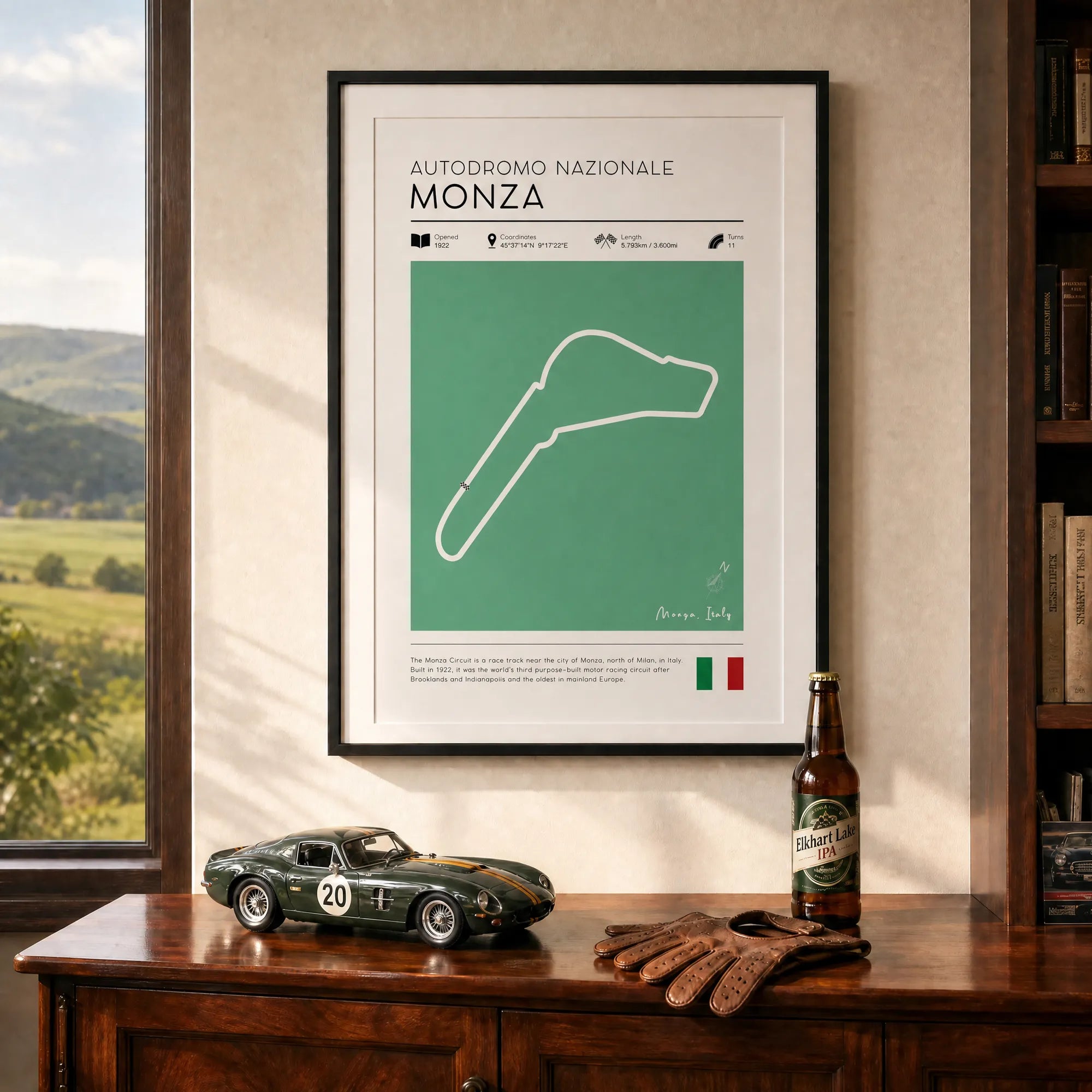 Framed f1 track wall art of Autodromo Nazionale Monza on a wall with a car model and beer bottle on a wooden surface.